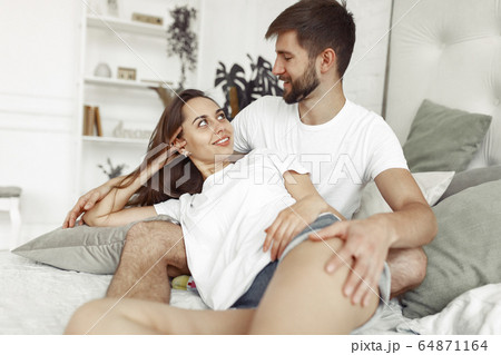 Couple sitting on a bed in a room Couple sitting on a bed in a room 64871164