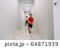 the boy runs down the hall of the house 64871939