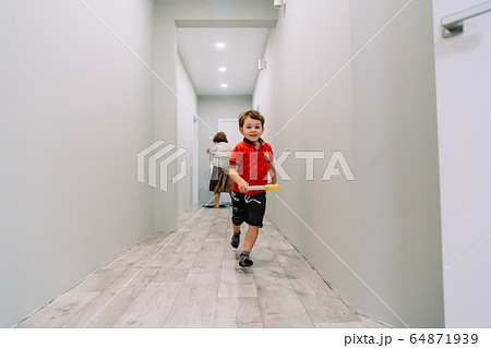 the boy runs down the hall of the house 64871939
