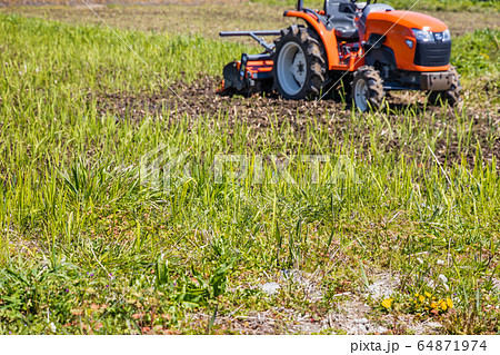 雑草の生えた畑とトラクター 64871974