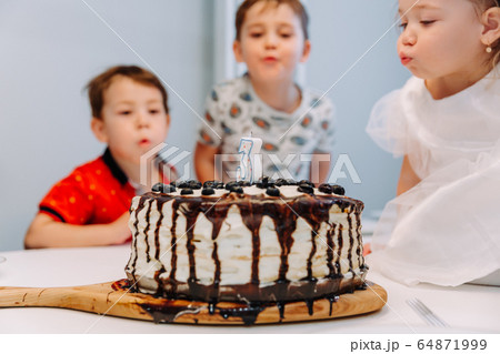 a little three-year-old girl blows out the candle on the cake a little three-year-old girl blows out the candle on the cake 64871999