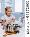 a little girl in a dress is preparing to blow out a candle on a birthday cake 64872000