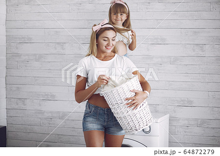 Mother and daughter in a bathroom near wash mashine Mother and daughter in a bathroom near wash mashine 64872279