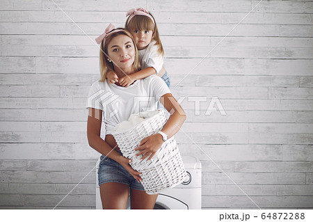 Mother and daughter in a bathroom near wash mashine 64872288