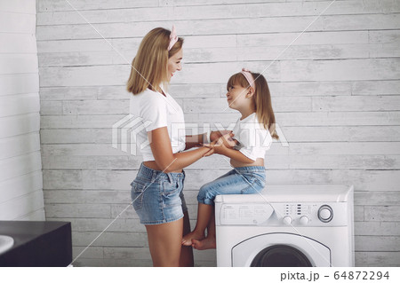 Mother and daughter in a bathroom near wash mashine Mother and daughter in a bathroom near wash mashine 64872294