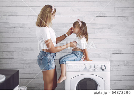 Mother and daughter in a bathroom near wash mashine 64872296
