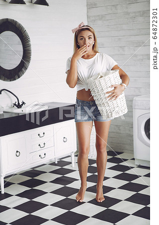 Woman in a bathroom near wash mashine 64872301