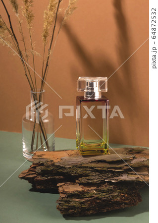 Natural and forest perfume in a bottle next to the bark of a tree. Natural and forest perfume in a bottle next to the bark of a tree. 64872532