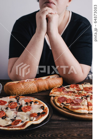 Overweight woman with big amount of junk food 64873083