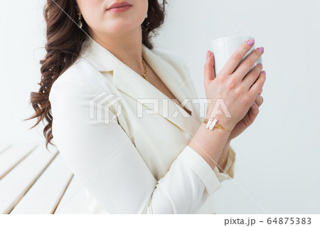 Close up of beautiful female hands holding big white cup of cappuccino coffee. 64875383