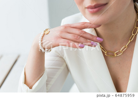 Close-up of beautiful woman wearing necklace and the pearl bracelet. Accessories, jewelry and bijouterie concept. Close-up of beautiful woman wearing necklace and the pearl bracelet. Accessories, jewelry and bijouterie concept. 64875959