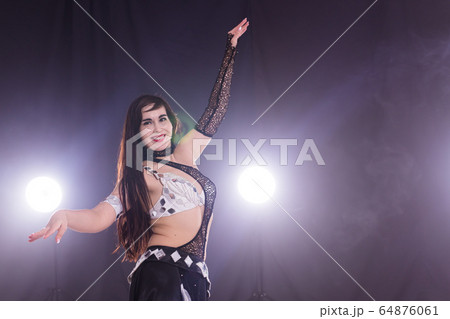 Young woman dancing in Tribal Fusion style. Belly dance on the stage. Copy space. 64876061