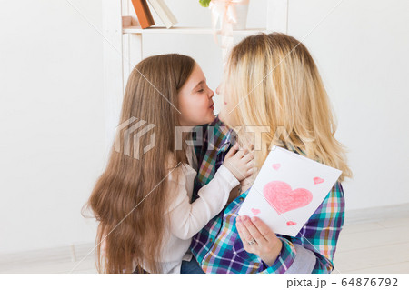 Mother's Day, holidays and family holidays - Mother holds greeting card from her lovely daughter. 64876792