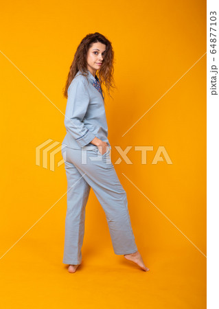 Smiling young girl in pajamas home wear posing while resting at home isolated on yellow background studio portrait. Relax good mood lifestyle concept. Smiling young girl in pajamas home wear posing while resting at home isolated on yellow background studio portrait. Relax good mood lifestyle concept. 64877103