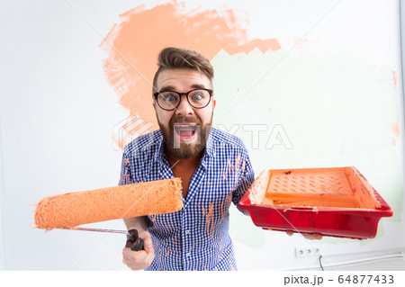 Funny man painting wall in her new apartment. Renovation and redecoration concept. Funny man painting wall in her new apartment. Renovation and redecoration concept. 64877433