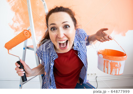 Renovation, redecoration and repair concept - Funny woman painting wall in new home. 64877999