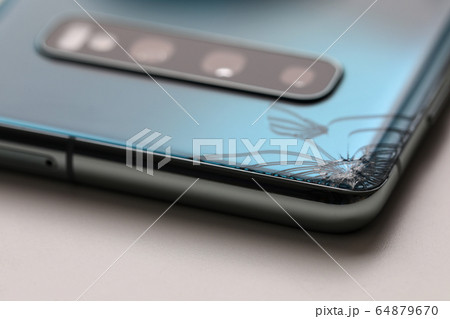 Modern smartphone lying at table with crack in corner 64879670