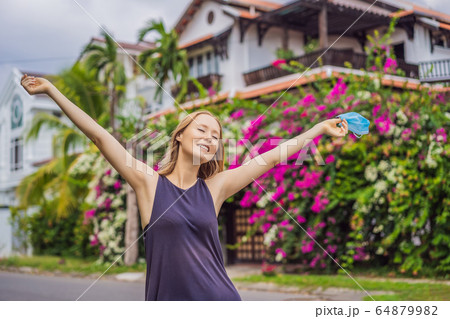Quarantine is over concept. Woman taking off mask against the background of small town houses. We 64879982