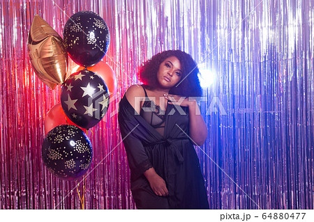 Portrait of a beautiful african american woman against twinkling background. Birthday party, nightclub and nightlife concept. 64880477