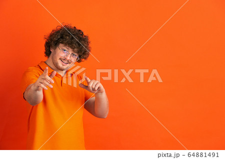 Caucasian young man's monochrome portrait on orange studio background Caucasian young man's monochrome portrait on orange studio background 64881491