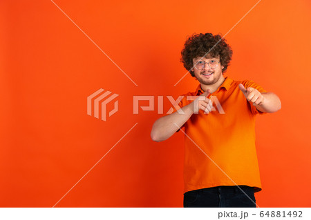 Caucasian young man's monochrome portrait on orange studio background Caucasian young man's monochrome portrait on orange studio background 64881492