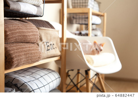 Bed sheets, duvet covers and towels are folded vertically. Metal and fabric black baskets. White sphinx cat. The concept of housework and storage. 64882447