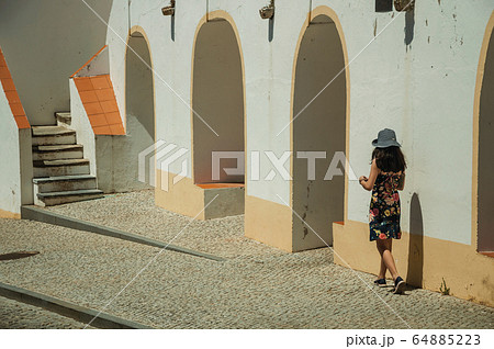 Little girl walking on sidewalk next to building in Elvas Little girl walking on sidewalk next to building in Elvas 64885223