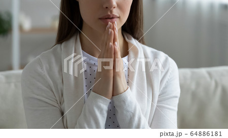 Close up of young woman praying at home 64886181