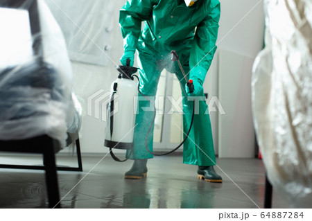 Specialist chlorinating the room in protective uniform stock photo Specialist chlorinating the room in protective uniform stock photo 64887284