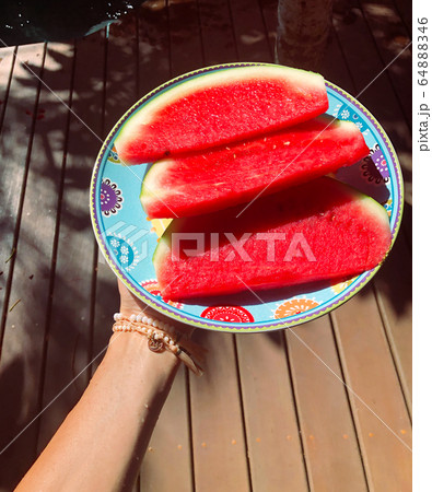 Young woman holding plate of watermelon slices Young woman holding plate of watermelon slices 64888346