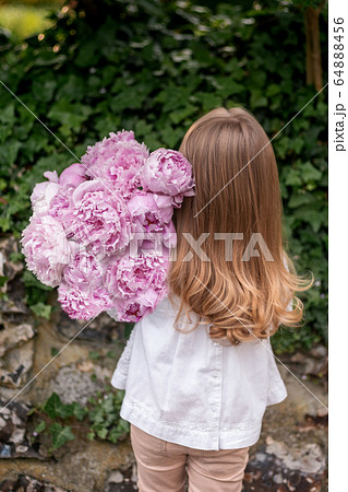 Girl holding a fresh pink peonies bouquet 64888456