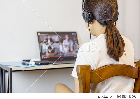 Social distancing woman wearing headphone during group video call with friends. Social distancing woman wearing headphone during group video call with friends. 64894906