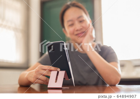 Social distancing happy smiling woman using cell phone video call family. 64894907