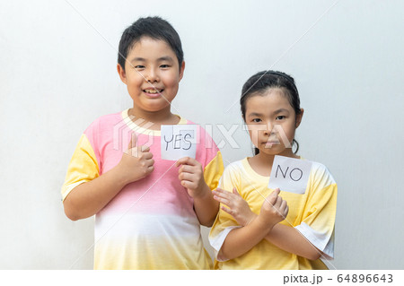 Boy holding paper with Yes. Girl holding paper Boy holding paper with Yes. Girl holding paper 64896643