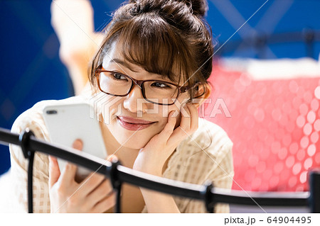 女性　寝室　ベッド　スマホ　部屋着　笑顔 64904495