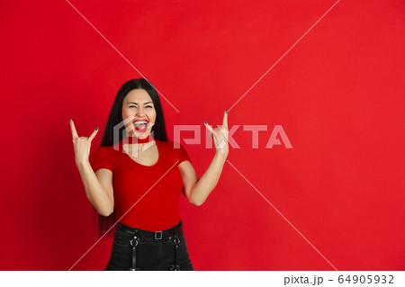 Caucasian young woman's monochrome portrait on red studio background, emotional and expressive 64905932