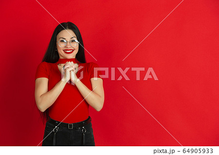 Caucasian young woman's monochrome portrait on red studio background, emotional and expressive Caucasian young woman's monochrome portrait on red studio background, emotional and expressive 64905933