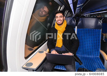 Arab man in train holds laptop and looks at camera Arab man in train holds laptop and looks at camera 64908085