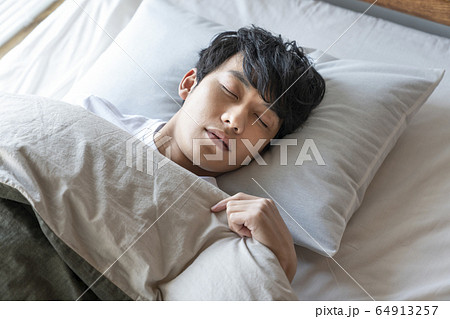 ベッドで眠る若い男性 64913257
