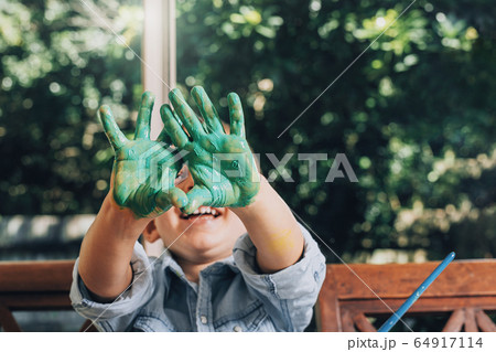 Boy with hands painted in green paints ready to make hand prints 64917114