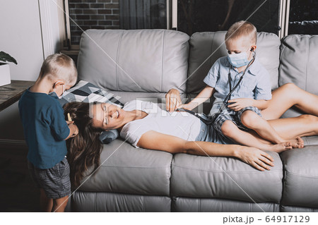 Cute little boys wearing medical facial masks playing as doctor and hairdresser with mom, staying at home 64917129
