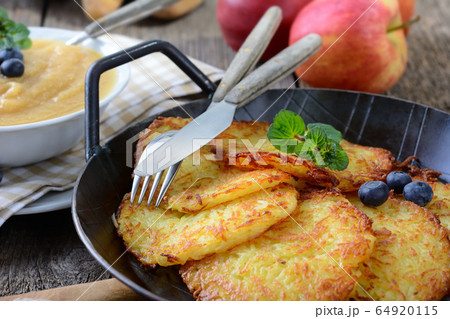 Homemade and crispy fried potato pancakes served in an iron pan with apple sauce 64920115