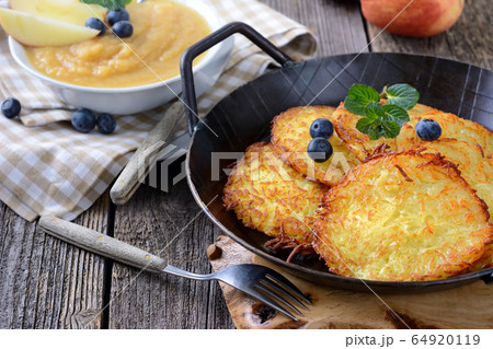 Homemade and crispy fried potato pancakes served in an iron pan with apple sauce 64920119