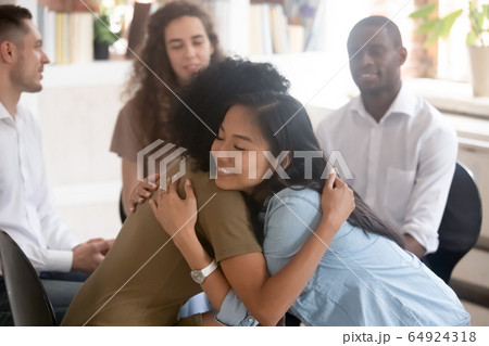 Asian and african women embracing giving psychological support during therapy 64924318