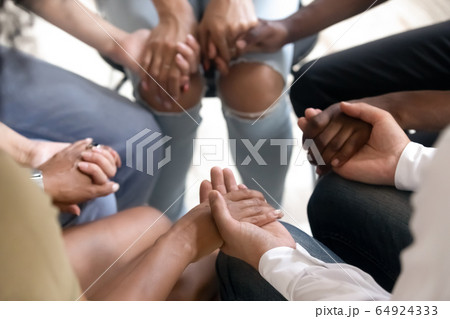 Diverse people sitting in circle holding hands at group therapy Diverse people sitting in circle holding hands at group therapy 64924333