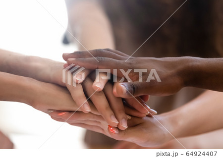 Diverse people group stacked joined hands in pile closeup view Diverse people group stacked joined hands in pile closeup view 64924407
