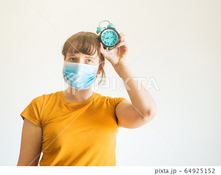 Young woman in protective face mask with clock Young woman in protective face mask with clock 64925152