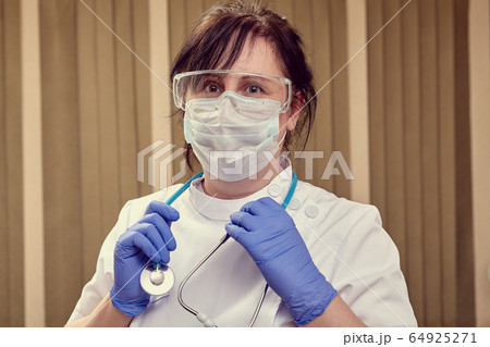 Female doctor uses personal protective equipment. Female doctor uses personal protective equipment. 64925271