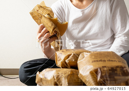 床に寝そべってハンバーガーを食う女　ぐうたら女　干物女　過食症イメージ 64927015