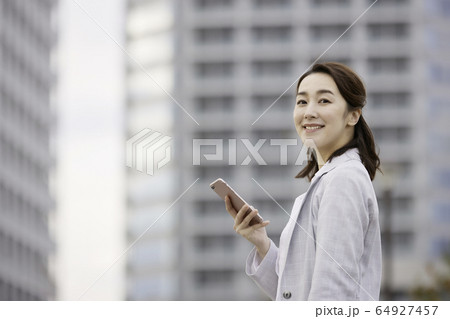 女性 ビジネス 屋外 スマホ 笑顔 女性 ビジネス 屋外 スマホ 笑顔 64927457